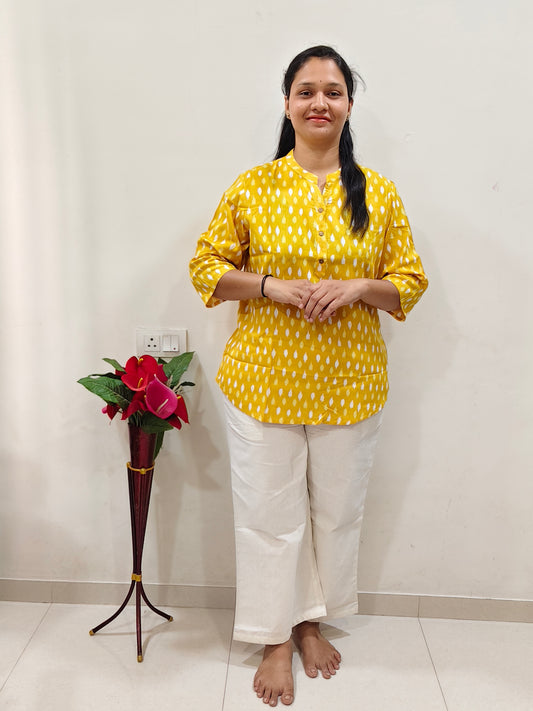Woman wearing a Cotton Short Kurti (Yellow) paired with comfortable white pants for a stylish look