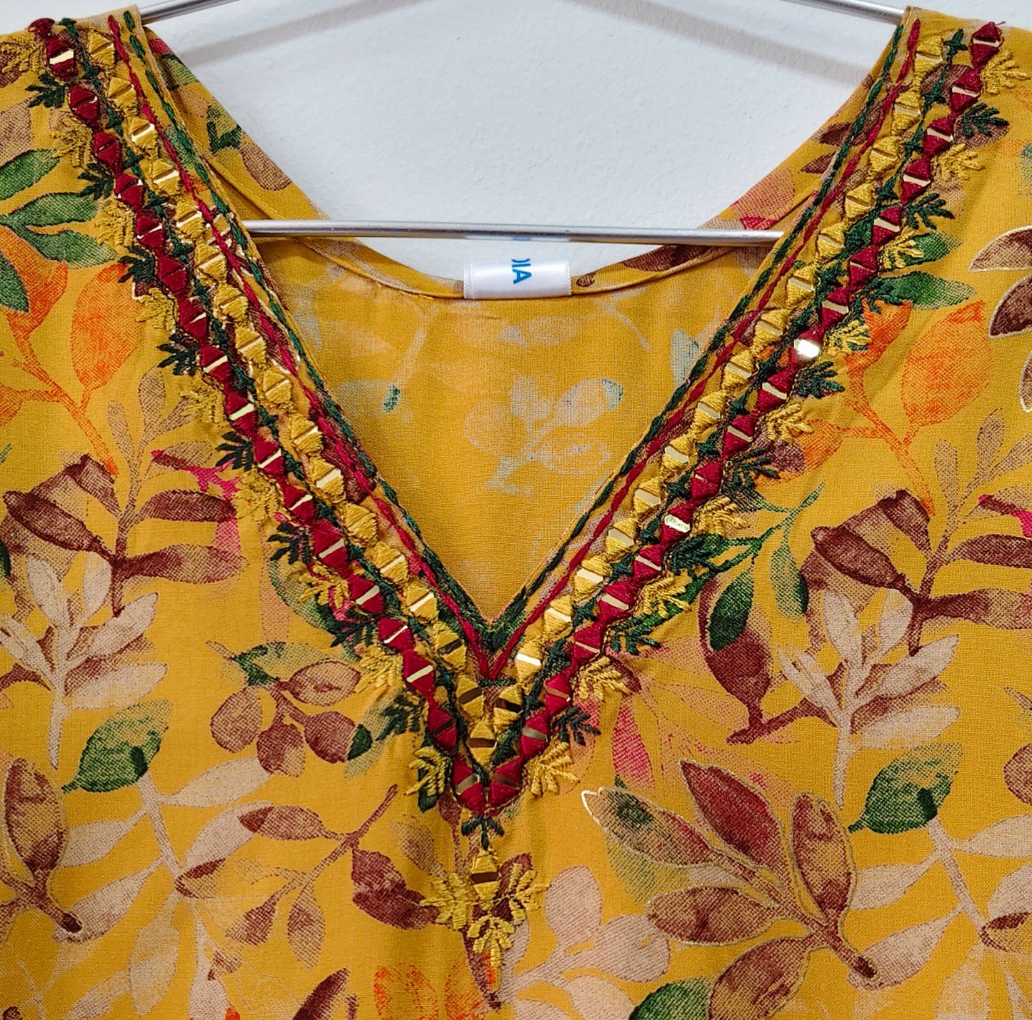 Mustard yellow mirror work kurti with intricate floral patterns and decorative neckline detailing