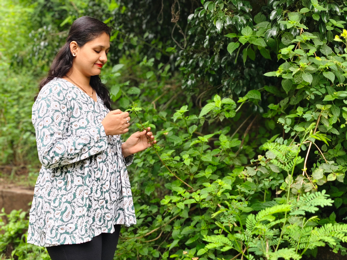 Woman in a garden wearing a pure cotton peplum top with a floral design, enjoying nature
