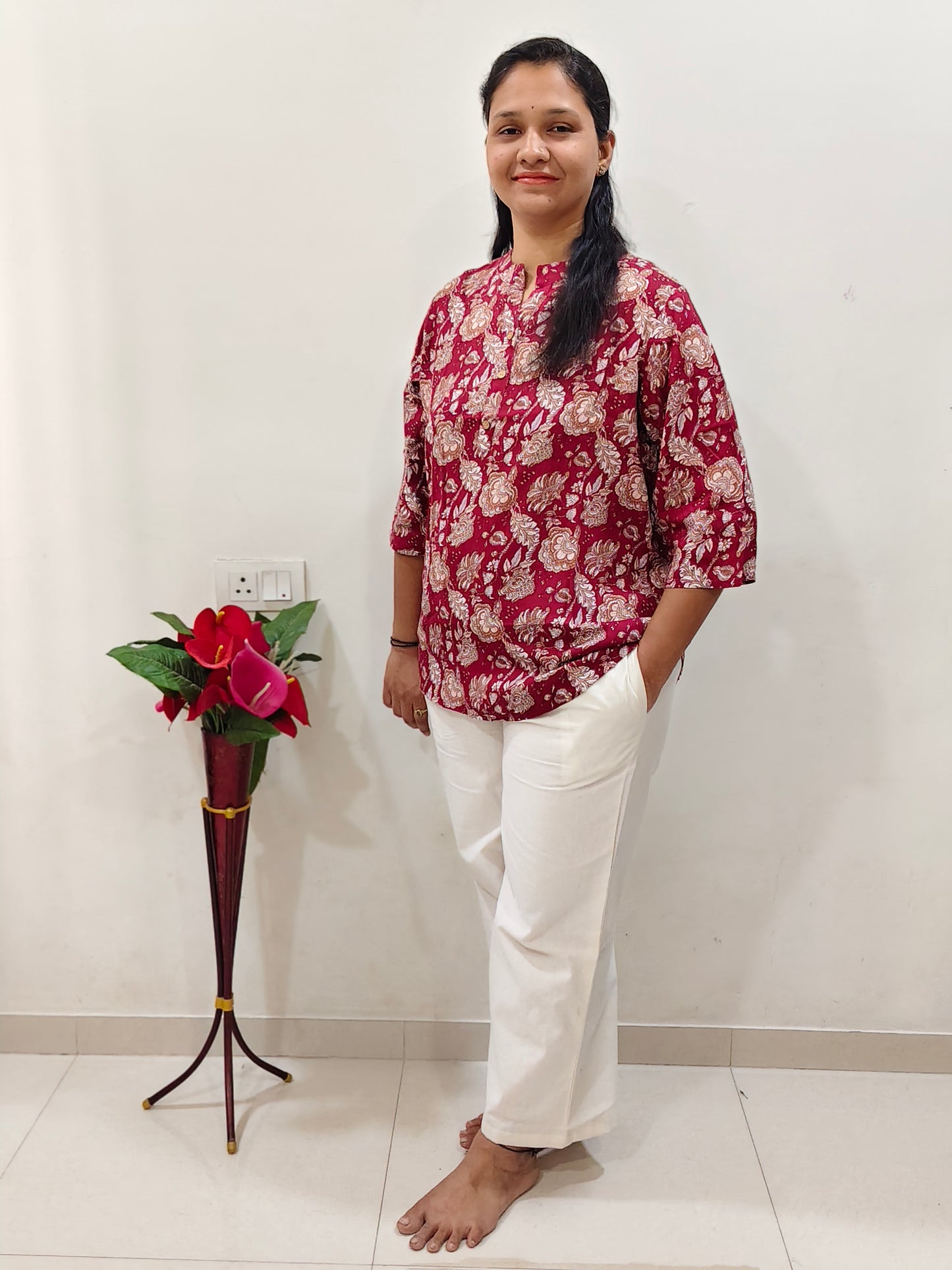 Woman modeling a Floral Cherry Red Cotton Short Kurti paired with white pants for a stylish look